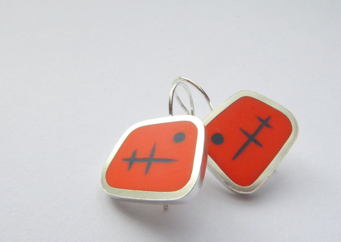 Picture of a pair of orange and silver geometric earrings with mid century design in ink blue resin