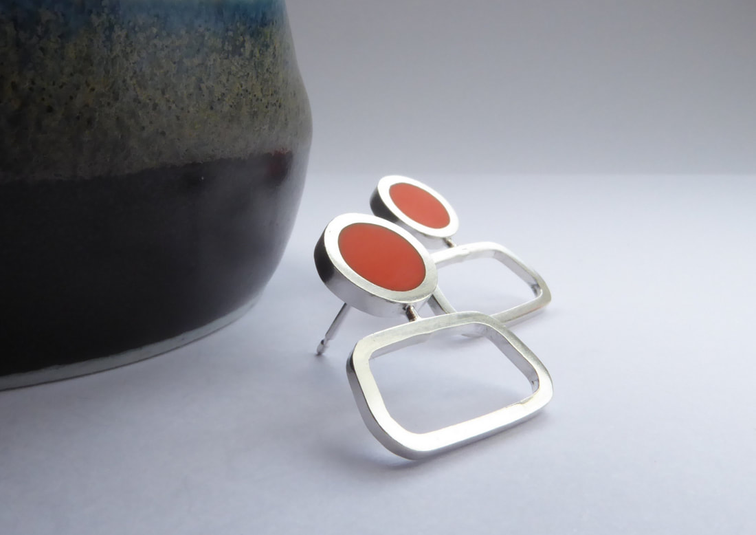 Picture of a pair of square silver stud earrings with orange resin